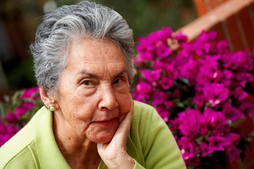 senior woman portrait with some flowers at the background